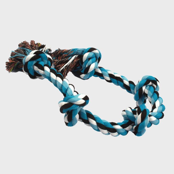 A multicolored rope toy lies coiled with knots, suitable for pet play in a neutral, light-colored setting.