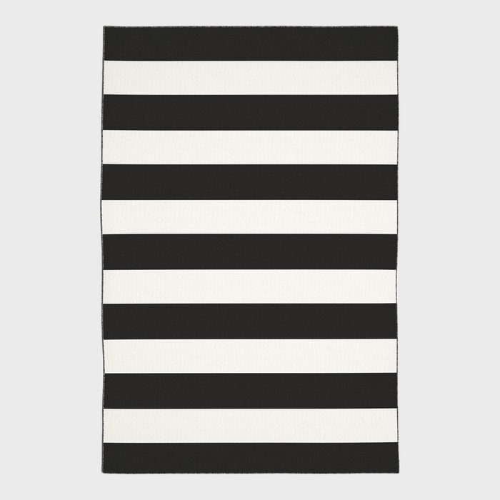 A rectangular rug displays alternating black and white horizontal stripes against a plain gray background.