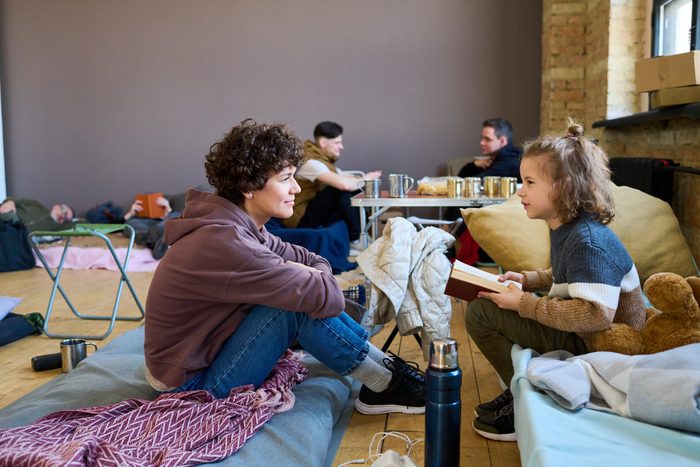 Young woman in casualwear listening to her little son with open book
