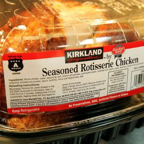 Rotisserie chicken sits in a clear plastic container labeled 
