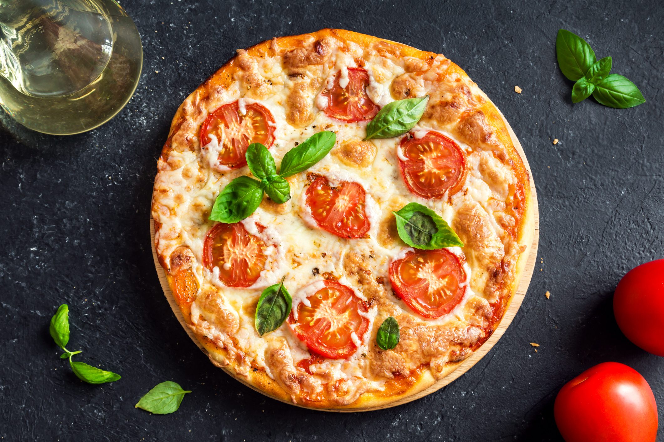 Pizza Margherita on black stone background. Homemade Pizza Margarita with Tomatoes, Basil and Mozzarella Cheese.