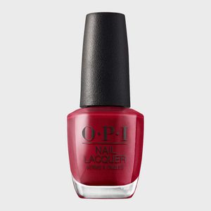 Red nail polish bottle stands upright with black cap on a plain gray background. Text on bottle: 
