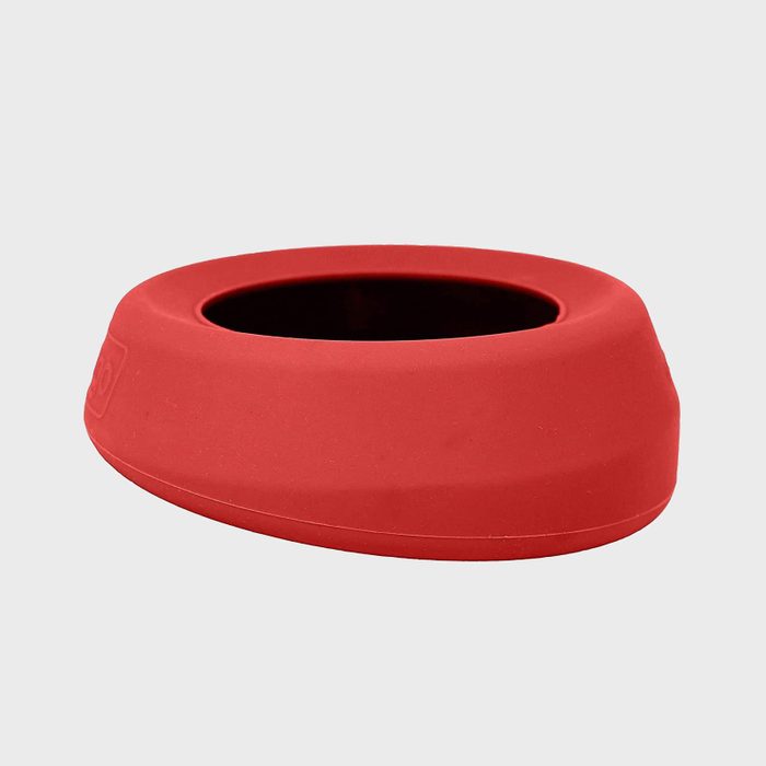 Red silicone ring resting on a flat, light gray background. The ring has a smooth surface and a wide, hollow center.