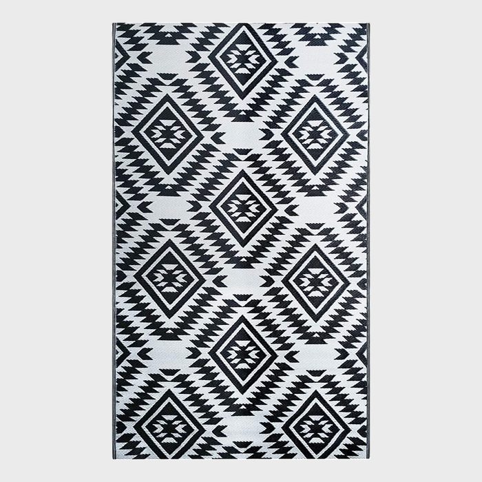 Geometric rug displays diamond patterns with zigzag designs, featuring black and white colors in a symmetrical arrangement.