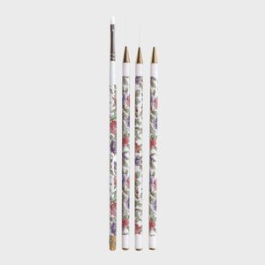 Four floral-patterned nail art brushes stand upright against a plain background.