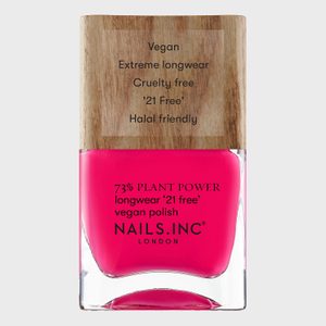 Nail polish bottle showcasing hot pink color; labeled vegan, cruelty-free, longwear, and halal-friendly; set against a wood-textured background.
