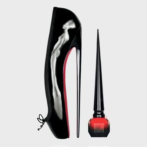 High-heeled shoe rests vertically, resembling a stiletto heel. Red-soled and black with a human silhouette design. Nearby, a tall black nail polish bottle.
