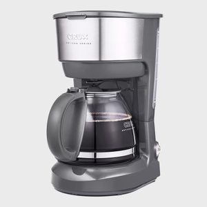 Coffee maker resting; glass carafe partially filled; sleek kitchen setting; text on top: 