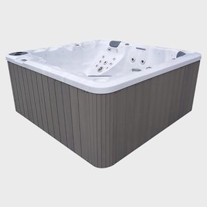 A large, empty hot tub with multiple jets sits on a plain, light grey background.