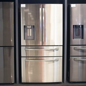 Three stainless steel refrigerators stand side-by-side in a display setting, each featuring double doors and ice dispensers.
