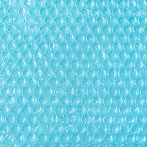 Blue bubble wrap sits flat, covering the entire image, displaying rows of raised, transparent bubbles.