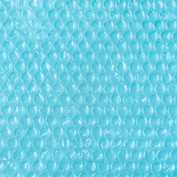 Blue bubble wrap sits flat, covering the entire image, displaying rows of raised, transparent bubbles.
