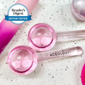 Pink cosmetic facial globes rest on a speckled countertop, surrounded by various beauty products. Text reads 