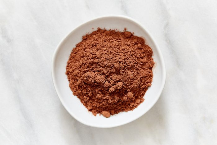 Brown powder sitting in a white bowl on a light, marbled surface.