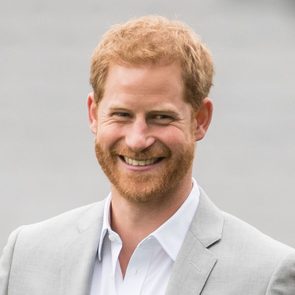 A man is smiling, wearing a light gray suit and white shirt, against a plain gray background.