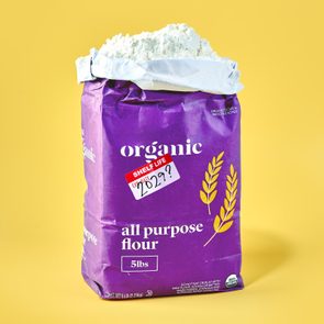 A purple flour bag stands upright on a yellow surface, labeled 