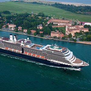 Cruise ship sails through a wide river, surrounded by lush green landscape and small buildings. Text reads 