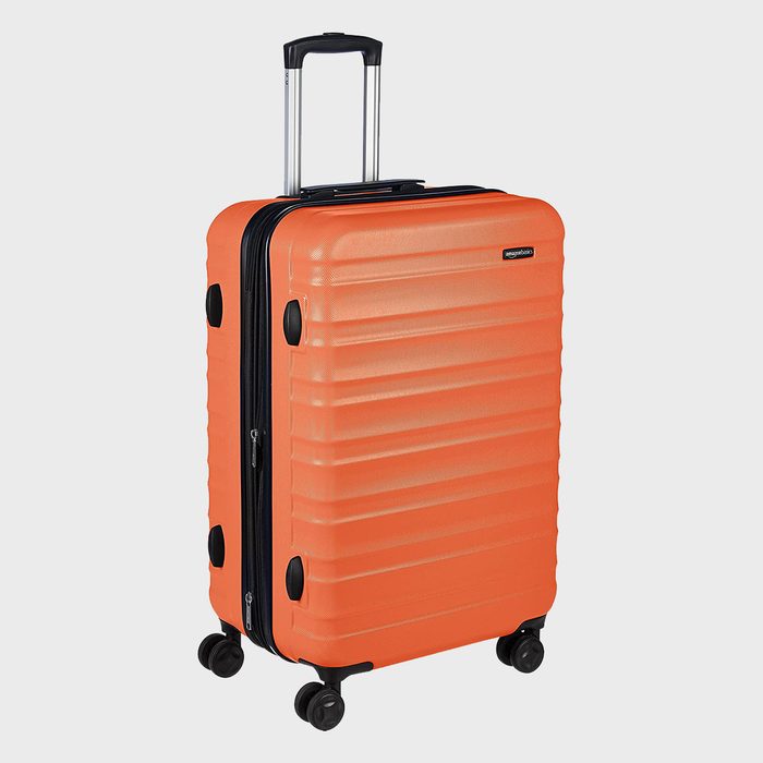 Orange suitcase stands upright, expanded with a black retractable handle, and four wheels. Set against a plain white background.