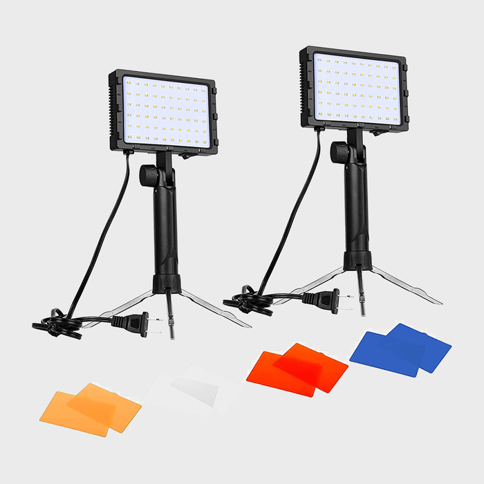 Two LED panel lights on tripods, connected by cables, with orange, white, red, and blue filters placed below them on a plain background.