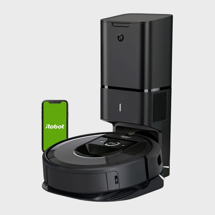 Robot vacuum sits on dock; a smartphone nearby displays 