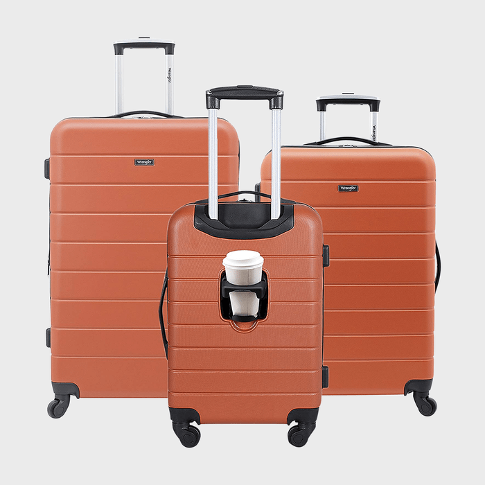 Three orange suitcases with wheels, one holding a coffee cup in its handle; set against a plain gray background.