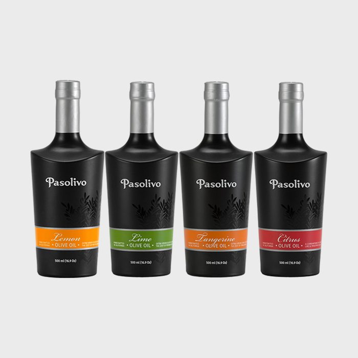 Four black olive oil bottles with silver caps stand in a row, labeled 