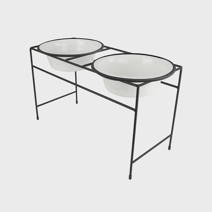 Two white bowls resting on a black metal stand against a plain white background.
