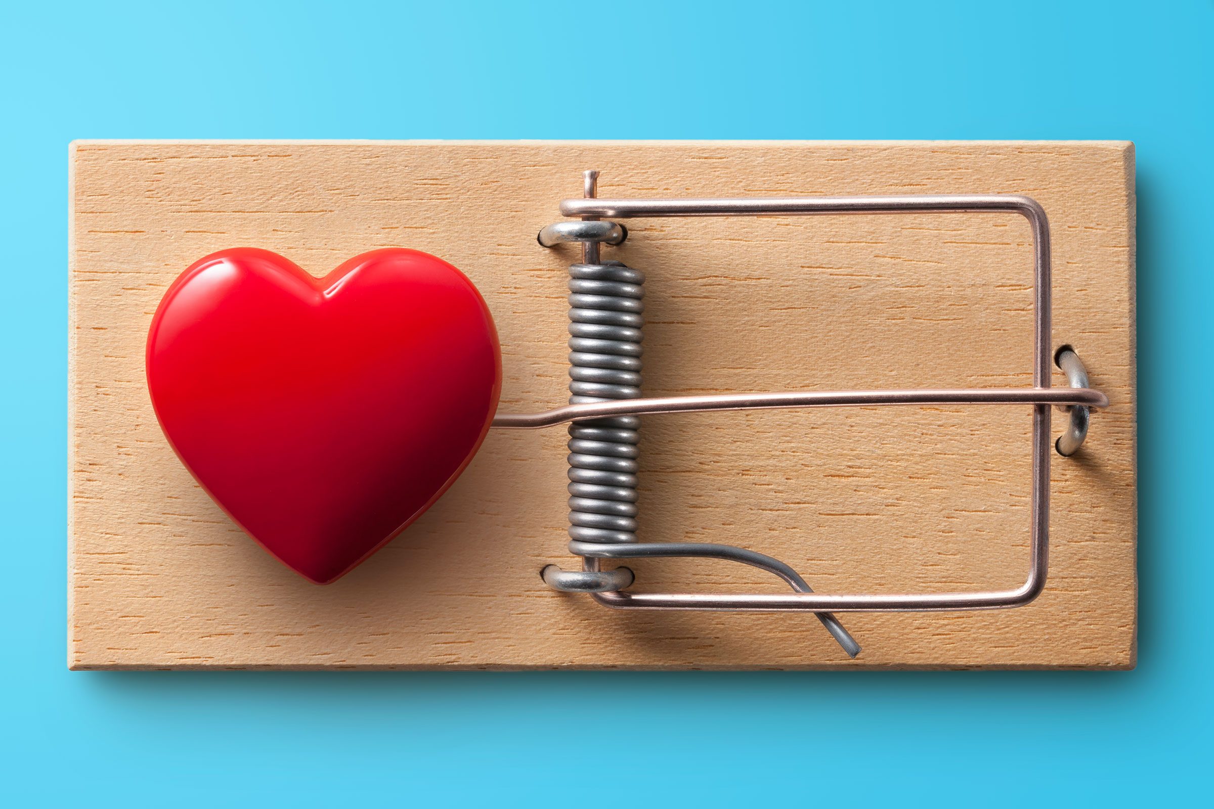 Red heart on a mouse trap, set against a blue background.