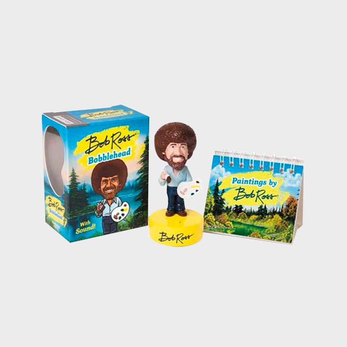 Bobblehead holding a palette, standing next to a colorful box and a mini art-themed calendar with landscape paintings.