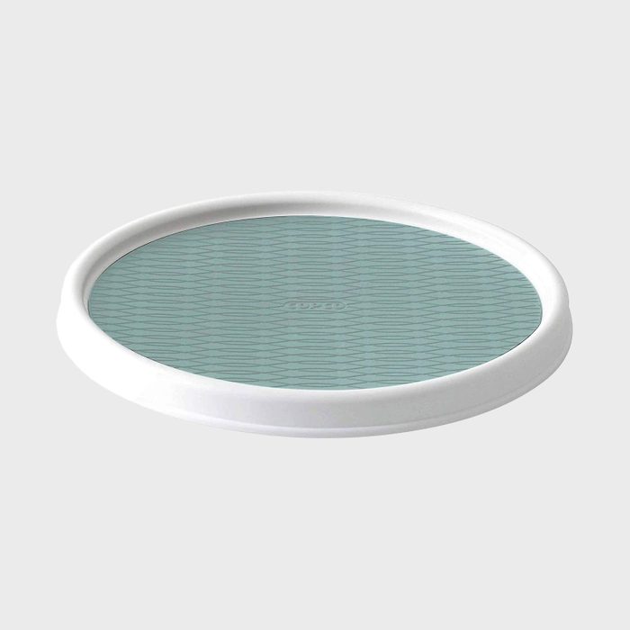 Circular tray resting, featuring a textured blue surface with a white rim on a plain background. Text on surface: 