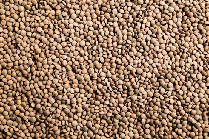 Brown lentils fill the entire frame, closely packed together, showing their round, flat shape and earthy tones.