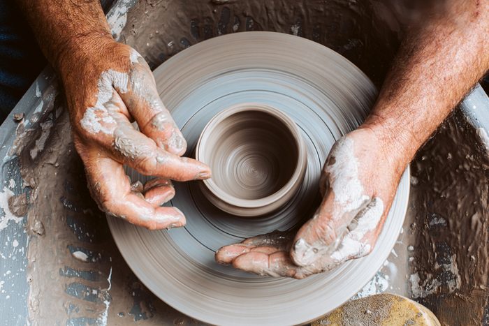 Potter's hands working clay on a potter's wheel