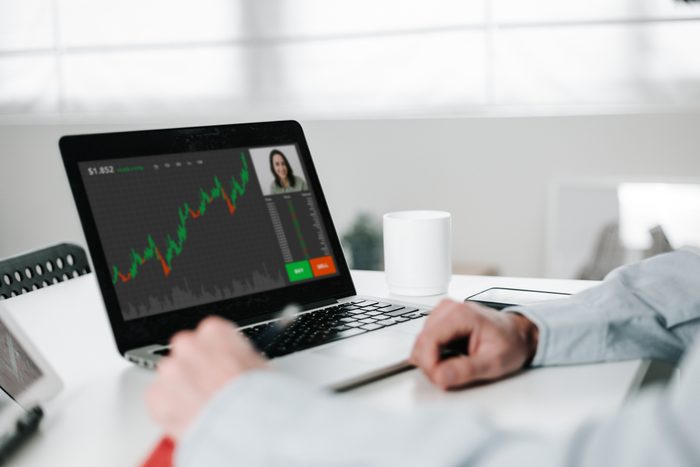 Young investor man working from home office having a video call with colleague to analyze data stock market