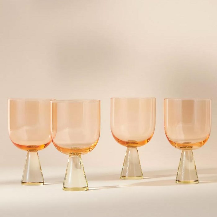 Four amber-toned glasses stand upright on cone-shaped bases, placed against a soft, neutral background.