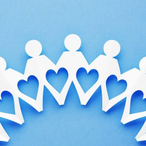 Paper chain figures holding hands, forming a circle with hearts between, against a light blue background.