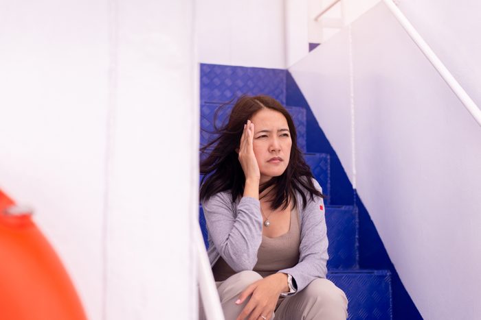 Woman suffering from sea sickness and feeling headache while on boat