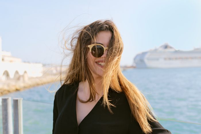 Head portrait of a beautiful young woman with her hair blown by the wind in front of the sea