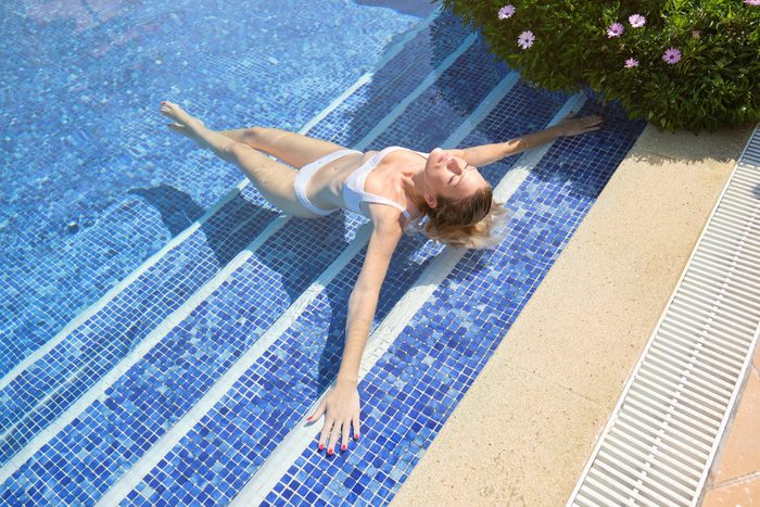 Carefree female lying on stairs in cooling pool