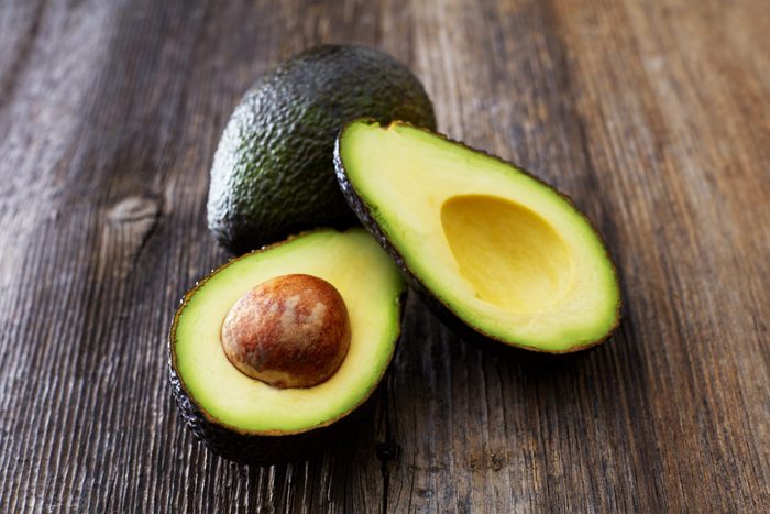 Whole and sliced avocado on wood