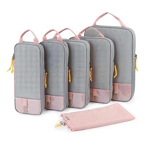 Five gray and pink packing cubes with yellow zipper pulls, arranged upright with an additional folded bag in front.