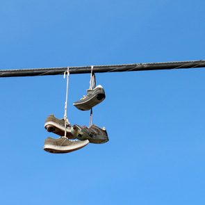 Shoes hang suspended on power lines against a clear blue sky.