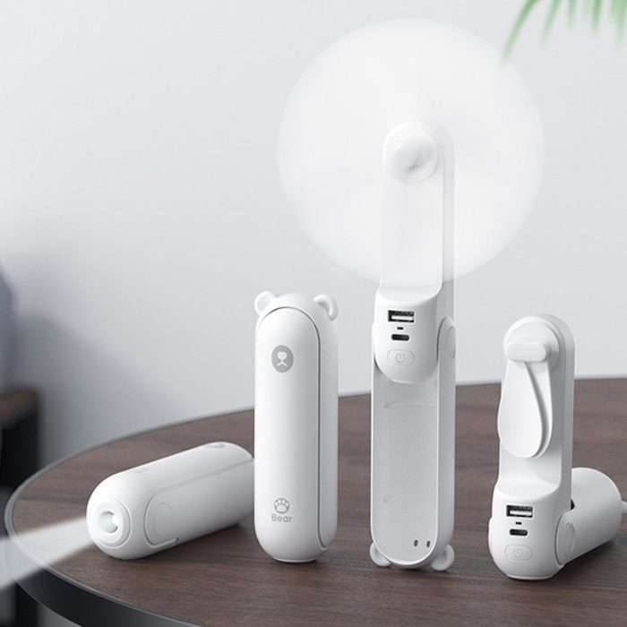 Small white fans, rotating gently, sit on a wooden table in a minimalistic room.