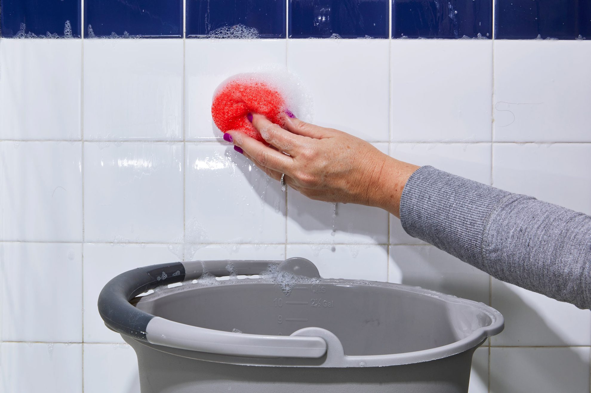 hand cleaning tile shower wall