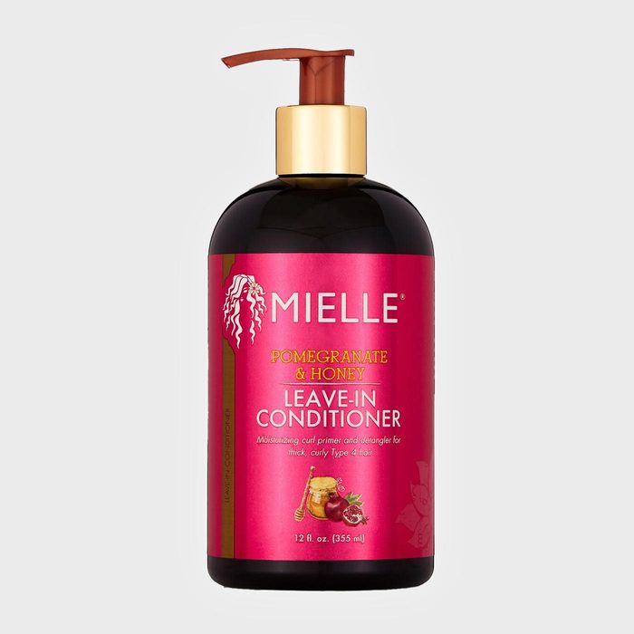 A bottle dispenses leave-in conditioner, featuring pomegranate and honey, for thick curly hair; labeled 
