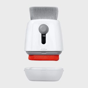 Dustpan and cleaning brush are suspended, separated; white and gray plastic against a plain background.