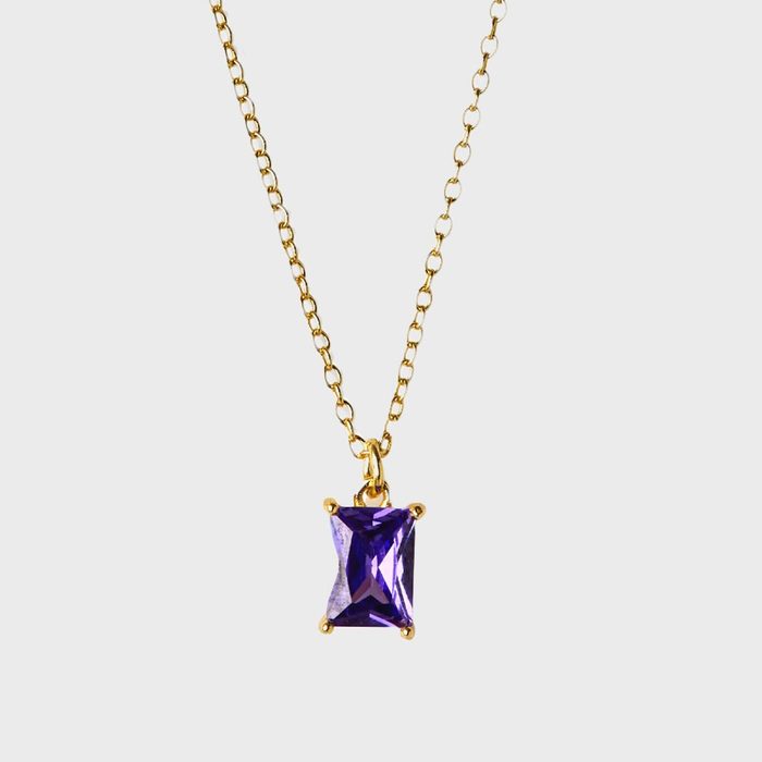 A gold chain necklace holds a rectangular purple gemstone pendant against a plain white background.