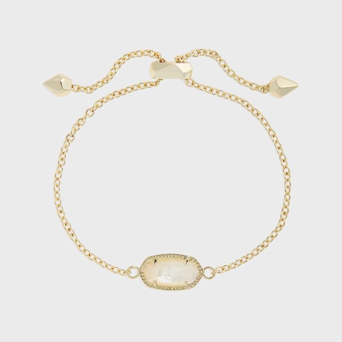 Gold bracelet features an oval gemstone centerpiece, adjustable chain with cone-shaped ends, on a white background.