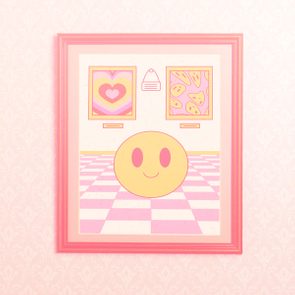 Framed artwork shows a smiling face on pink checkered floor, two abstract paintings hang on a patterned wallpaper background.