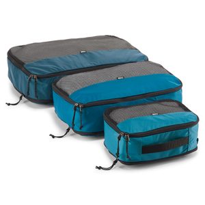 Three blue packing cubes, varying sizes, sit on a white background. They feature mesh tops and black zippers with pull cords.