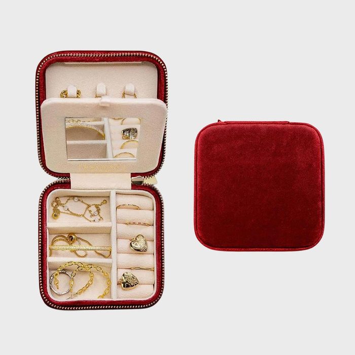 Jewelry case holds gold accessories, open to show organized slots with necklaces, bracelets, rings; next to it, a closed red velvet case.